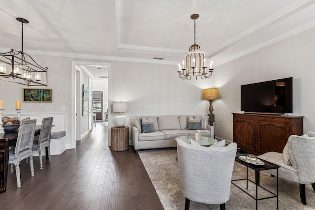 living area featuring a tray ceiling, crown molding, dark wood finished floors, visible vents, and an inviting chandelier