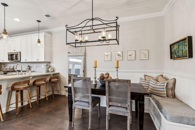 dining room featuring dark wood-style floors, ornamental molding, wainscoting, and visible vents