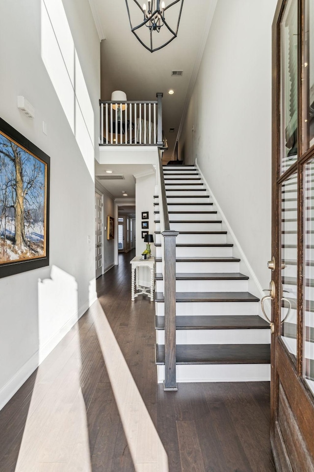 stairway featuring baseboards, visible vents, ornamental molding, wood finished floors, and a chandelier