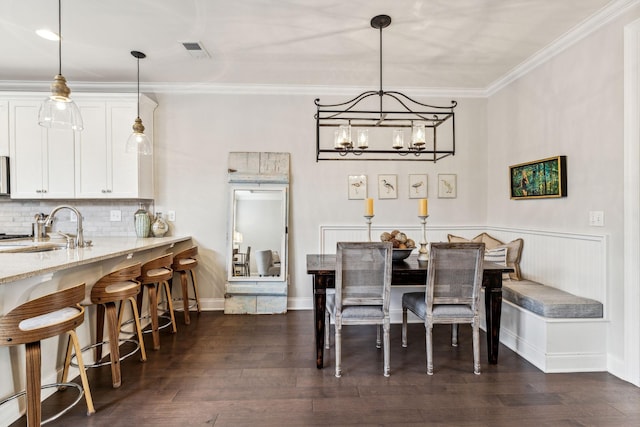 dining room featuring dark wood-style flooring, visible vents, crown molding, and baseboards