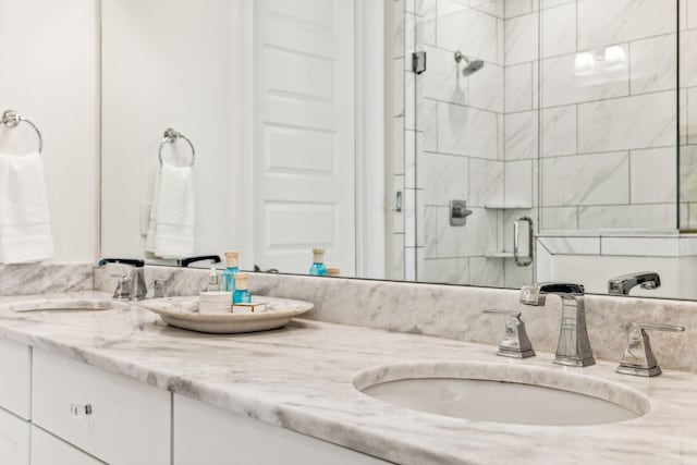 full bath featuring double vanity, a stall shower, and a sink