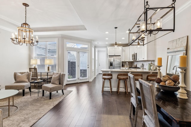 dining area featuring ornamental molding, dark wood-style flooring, an inviting chandelier, a tray ceiling, and recessed lighting