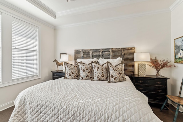 bedroom with ornamental molding, a tray ceiling, baseboards, and dark wood-style floors