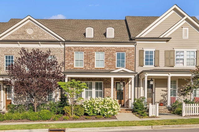 townhome / multi-family property featuring brick siding and roof with shingles