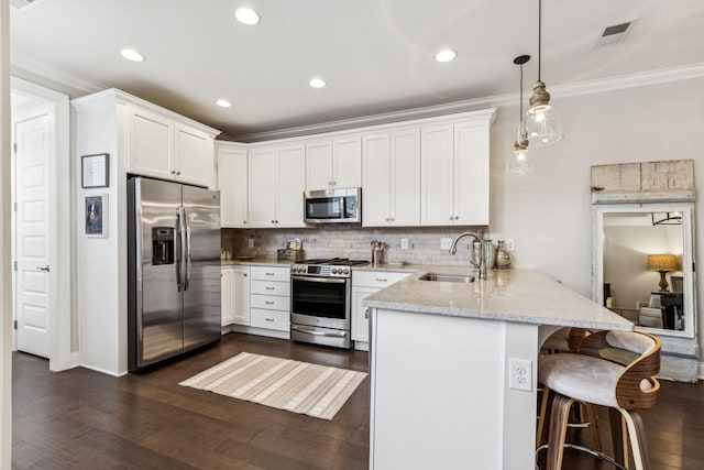 kitchen featuring a peninsula, white cabinetry, appliances with stainless steel finishes, and a sink