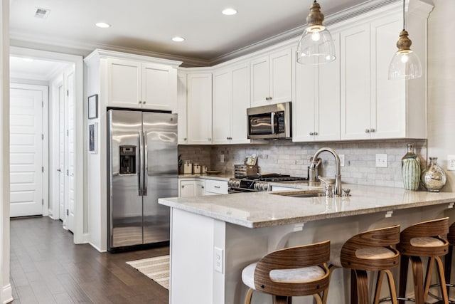 kitchen featuring hanging light fixtures, white cabinetry, appliances with stainless steel finishes, and light stone counters