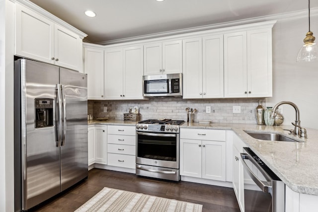 kitchen with stainless steel appliances, white cabinetry, a sink, and hanging light fixtures