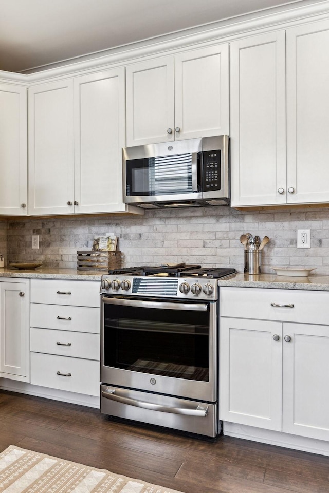 kitchen with stainless steel appliances, white cabinetry, light stone counters, and tasteful backsplash