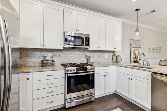 kitchen featuring pendant lighting, stainless steel appliances, white cabinets, a sink, and light stone countertops