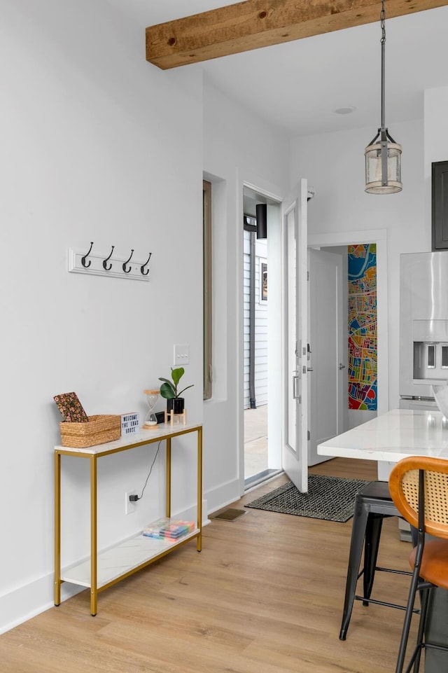 interior space with light wood finished floors, baseboards, and beamed ceiling