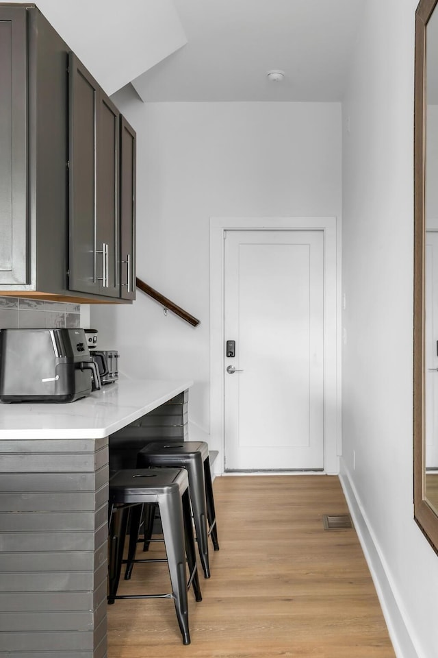 bar featuring baseboards, visible vents, and light wood finished floors