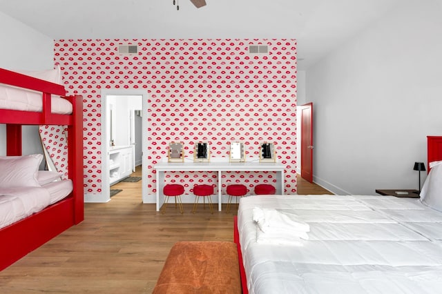 bedroom featuring ceiling fan, visible vents, connected bathroom, and wood finished floors