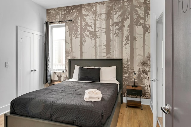 bedroom with light wood-type flooring, baseboards, and a closet