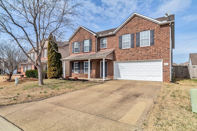 traditional home featuring a garage, concrete driveway, brick siding, and fence