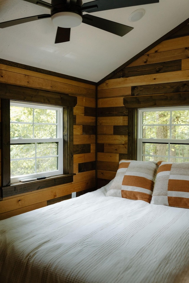 bedroom featuring lofted ceiling and wood walls