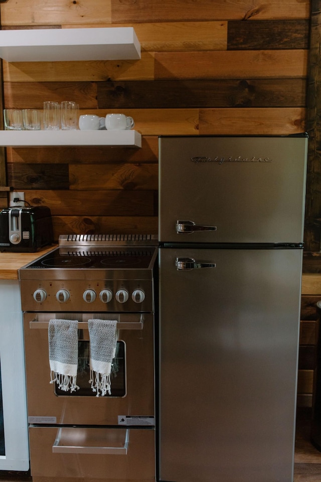 kitchen featuring wooden walls and appliances with stainless steel finishes