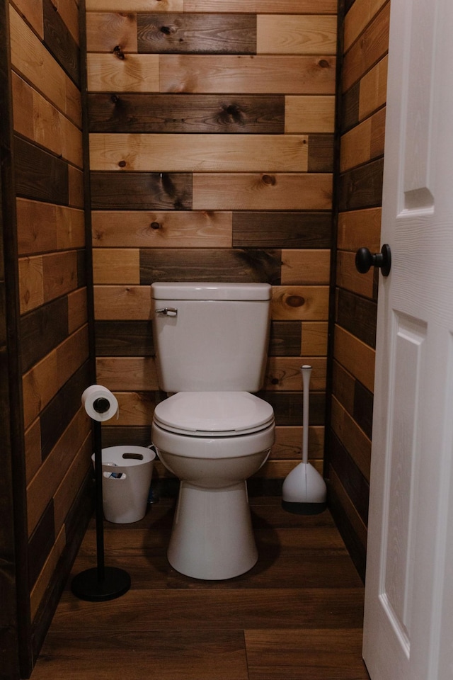 bathroom featuring wood walls, toilet, and wood finished floors