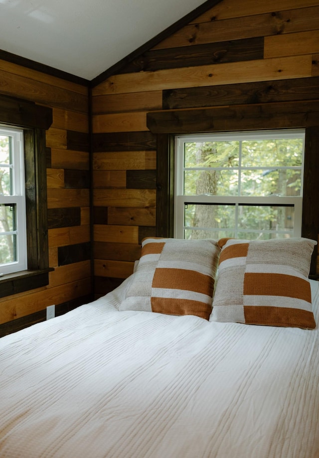 bedroom featuring vaulted ceiling and wood walls