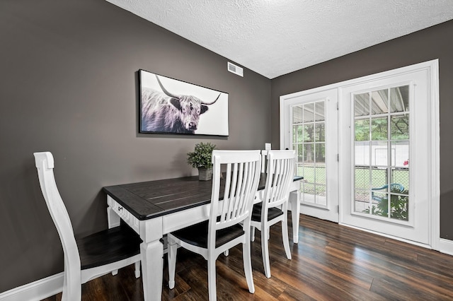 dining room featuring baseboards, a textured ceiling, visible vents, and wood finished floors