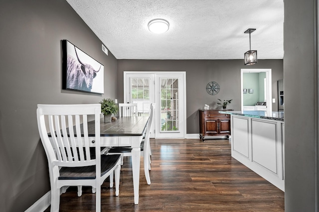 dining room with dark wood-type flooring, visible vents, a textured ceiling, and baseboards