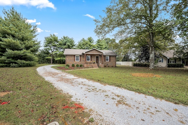 ranch-style home with a front yard, driveway, and fence