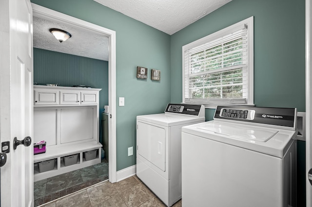 washroom featuring laundry area, baseboards, a textured ceiling, and washing machine and clothes dryer