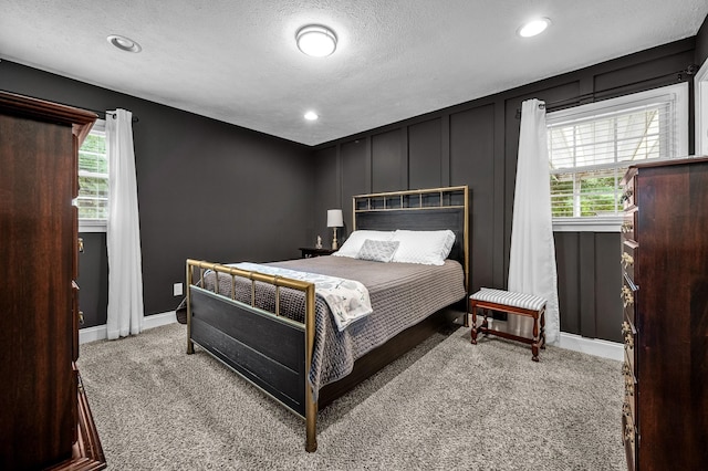 bedroom with carpet, recessed lighting, a decorative wall, a textured ceiling, and baseboards