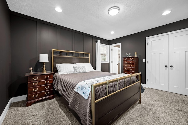 bedroom with a textured ceiling, carpet flooring, a decorative wall, a closet, and recessed lighting