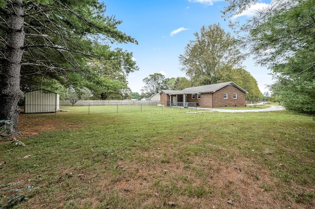 view of yard featuring fence, an outdoor structure, and a shed