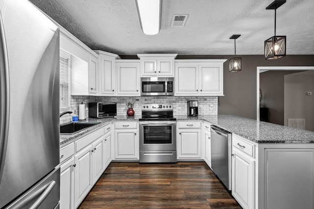 kitchen featuring visible vents, appliances with stainless steel finishes, dark wood-style flooring, a peninsula, and a sink