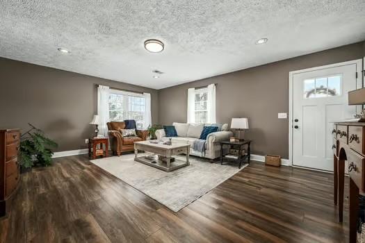 living room with a textured ceiling, baseboards, and wood finished floors