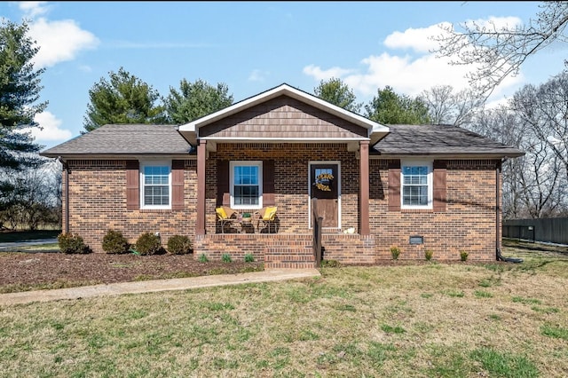 view of front of property with roof with shingles, crawl space, covered porch, a front lawn, and brick siding