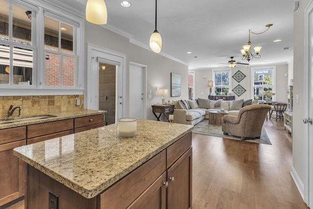 2112 Acklen Ave Unit 201, Nashville, TN 37212 - kitchen with brown cabinetry, ornamental molding, decorative light fixtures, a center island, and a sink