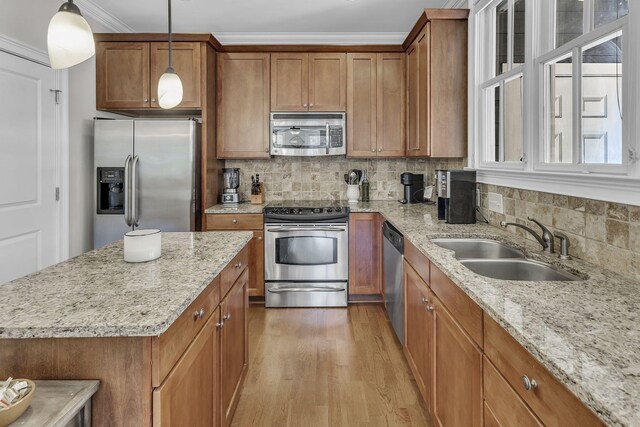 2112 Acklen Ave Unit 201, Nashville, TN 37212 - kitchen featuring brown cabinetry, appliances with stainless steel finishes, light stone counters, hanging light fixtures, and a sink