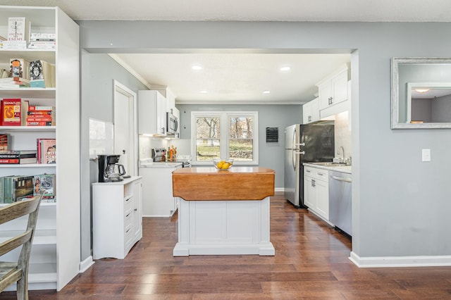 kitchen with stainless steel appliances, dark wood-style flooring, a kitchen island, white cabinetry, and light countertops