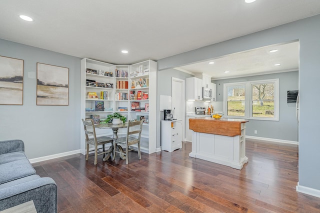 kitchen featuring dark wood-type flooring, butcher block counters, white cabinetry, baseboards, and appliances with stainless steel finishes