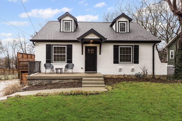 view of front of home featuring a patio area, brick siding, a shingled roof, and a front yard