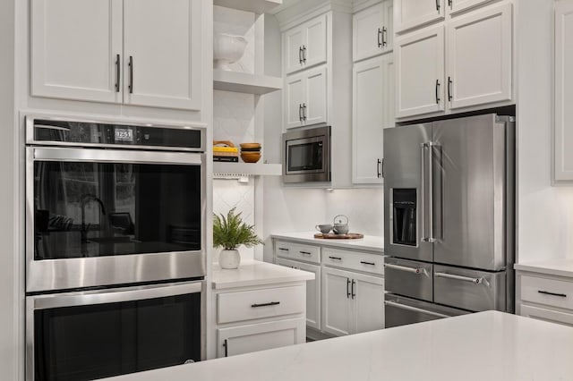 kitchen with open shelves, light countertops, backsplash, appliances with stainless steel finishes, and white cabinets