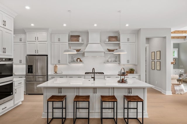 kitchen with custom exhaust hood, open shelves, stainless steel appliances, tasteful backsplash, and light countertops