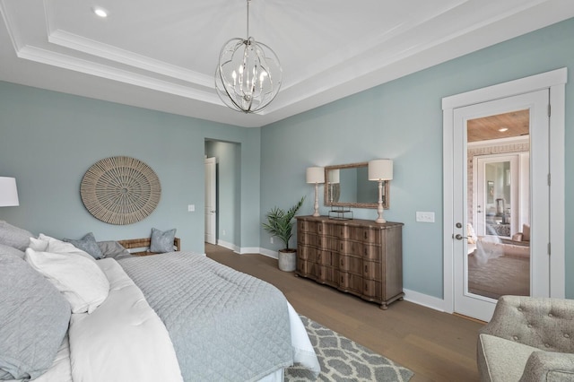 bedroom featuring a chandelier, a tray ceiling, wood finished floors, and baseboards