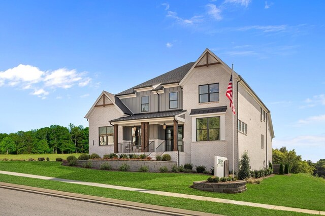 view of front of property with brick siding, a porch, a standing seam roof, and a front lawn