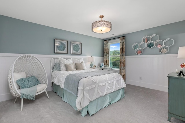 carpeted bedroom featuring a wainscoted wall