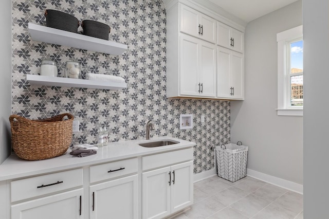 laundry room with cabinet space, baseboards, hookup for a washing machine, a sink, and light tile patterned flooring