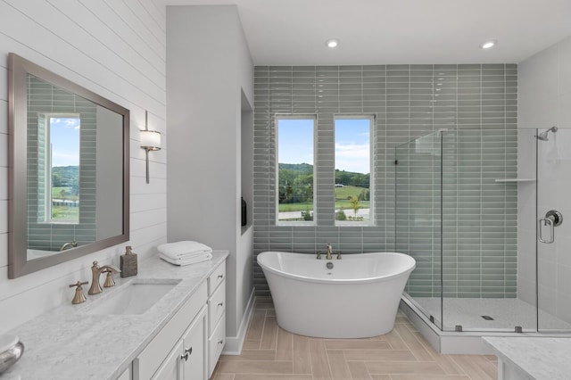 bathroom with a freestanding bath, a shower stall, vanity, and recessed lighting