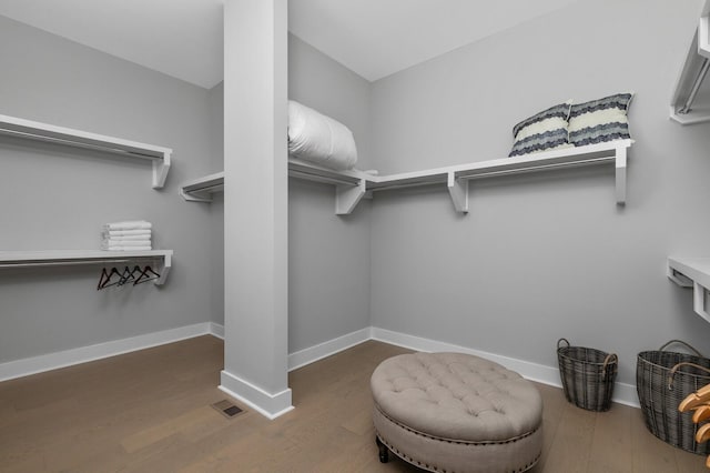 walk in closet featuring wood finished floors, visible vents, and ornate columns