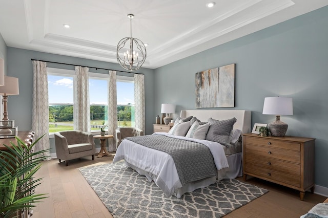 bedroom with an inviting chandelier, baseboards, a tray ceiling, and wood finished floors