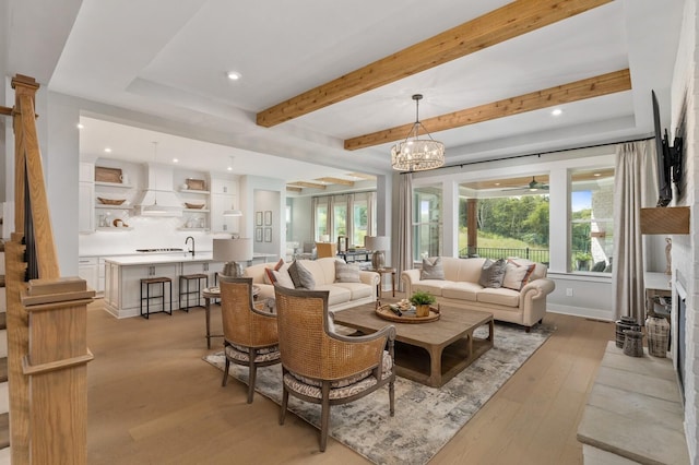 living area with a ceiling fan, baseboards, beam ceiling, recessed lighting, and light wood-type flooring