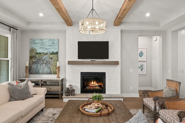 living room with an inviting chandelier, a brick fireplace, wood finished floors, beamed ceiling, and baseboards