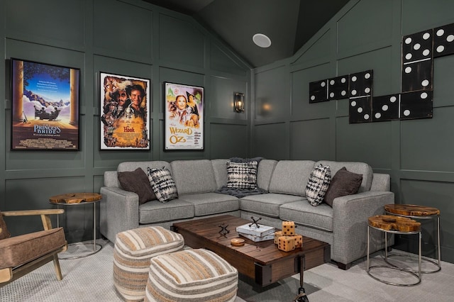 home theater room featuring lofted ceiling, a decorative wall, and carpet flooring