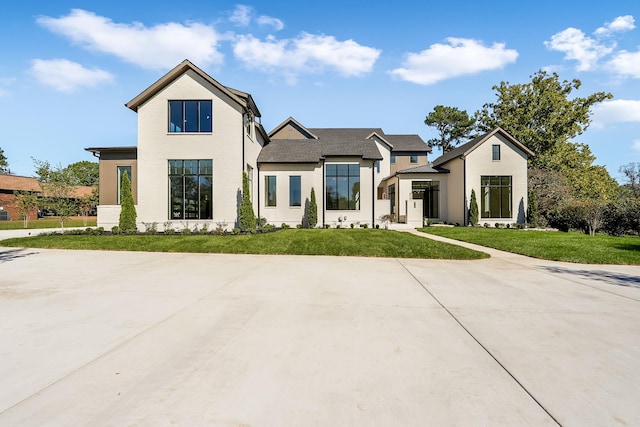 modern inspired farmhouse with a front lawn and stucco siding